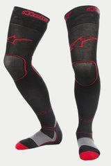 Alpinestars MX Long Tech Thick Socks, calzini da motocross, nero e rosso, con loghi Alpinestars rossi sulla coscia e sul bordo, tallone grigio e punta rossa, lunghezza a metà coscia con zone in mesh specializzate, strato base tecnico per gare fuoristrada
