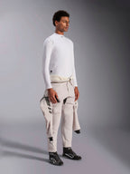Alpinestars ZX Evo V3 Top a maniche lunghe, base layer per auto racing bianco resistente alle fiamme, indossato da un modello con una tuta da gara legata in vita, strato tecnico leggero con collo a lupetto e dettaglio del logo.