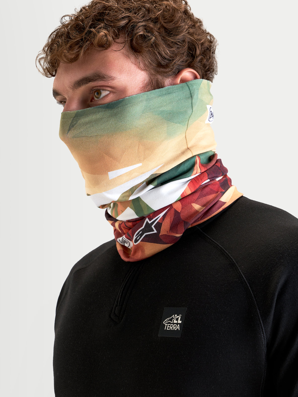 Alpinestars Buff Peaks Primaloft Neck Tube, scaldacollo da moto marrone e verde, indossato da un modello, con struttura isolante in tessuto tecnico traspirante per la guida con tempo fresco