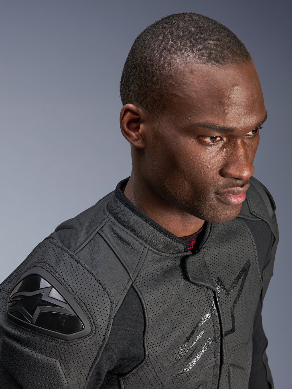 Primo piano di un modello che indossa la giacca in pelle Alpinestars Dusk Airflow, colore nero su nero, con ampia pelle traforata per la traspirabilità, slider esterni DFS sulle spalle e un design moderno per la guida sportiva.