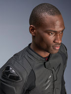 Primo piano di un modello che indossa la giacca in pelle Alpinestars Dusk Airflow, colore nero su nero, con ampia pelle traforata per la traspirabilità, slider esterni DFS sulle spalle e un design moderno per la guida sportiva.