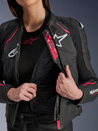 Giacca in pelle Alpinestars Stella Dusk da donna, nero, Diva Pink e bianco, giacca da moto in pelle aperta per mostrare la fodera termica trapuntata interna e il marchio Tech-Air Ready, con loghi bianchi e vivaci accenti rosa.