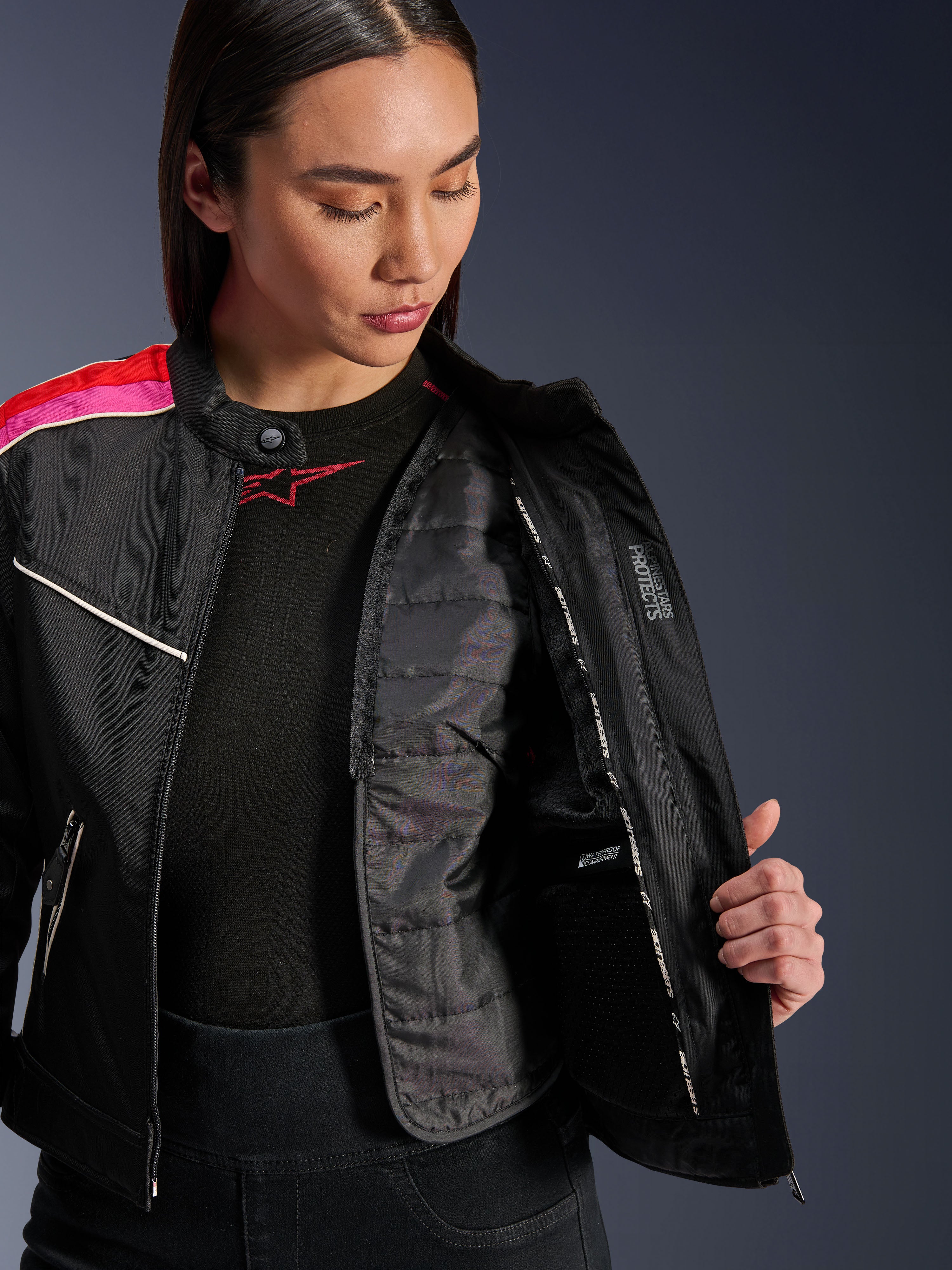 Giacca Alpinestars Stella T-Dyno WR, giacca da moto in tessuto nero, rosso brillante e fucsia, aperta per mostrare il gilet termico trapuntato interno e la tasca impermeabile, vestibilità biker d'ispirazione vintage per donna