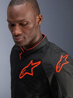 Giacca Alpinestars Viper Air V4, nero e rosso fluo, indossata da un modello uomo, primo piano che mostra i pannelli in tessuto a rete e i loghi Alpinestars rosso fluorescente brillante sul petto e sulla spalla, abbigliamento sportivo da moto