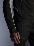 Alpinestars Troop-Air Pro Jacket, giacca tecnica traforata premium, nero, grigio cenere e rosso brillante, con costruzione in mesh tecnologico 2D per la ventilazione, pannelli delle maniche grigio cenere, dettaglio della zip rossa e polsini con asola per il pollice integrata, indossata con pantaloni coordinati.
