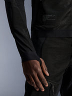 Alpinestars Troop-Air Jacket, nero, primo piano della costruzione in mesh tecnico, patch logata con testo tecnico e manica con passante per il pollice integrato, giacca da moto urbana estiva ad alto flusso d'aria