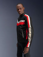 Modello uomo che indossa la giacca Alpinestars T-Dyno Air in nero, rosso acceso ed ecru, giacca da moto in tessuto d'ispirazione vintage con pannelli in mesh 3D, audaci strisce rosse e bianco sporco e marchio Alpinestars sulla manica.