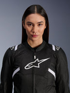Modella che indossa la giacca Alpinestars Stella T-SPS Air V2, giacca da moto da donna, nero e bianco, con pannelli in mesh traspirante e logo Alpinestars bianco sul petto, design sportivo per guida su strada