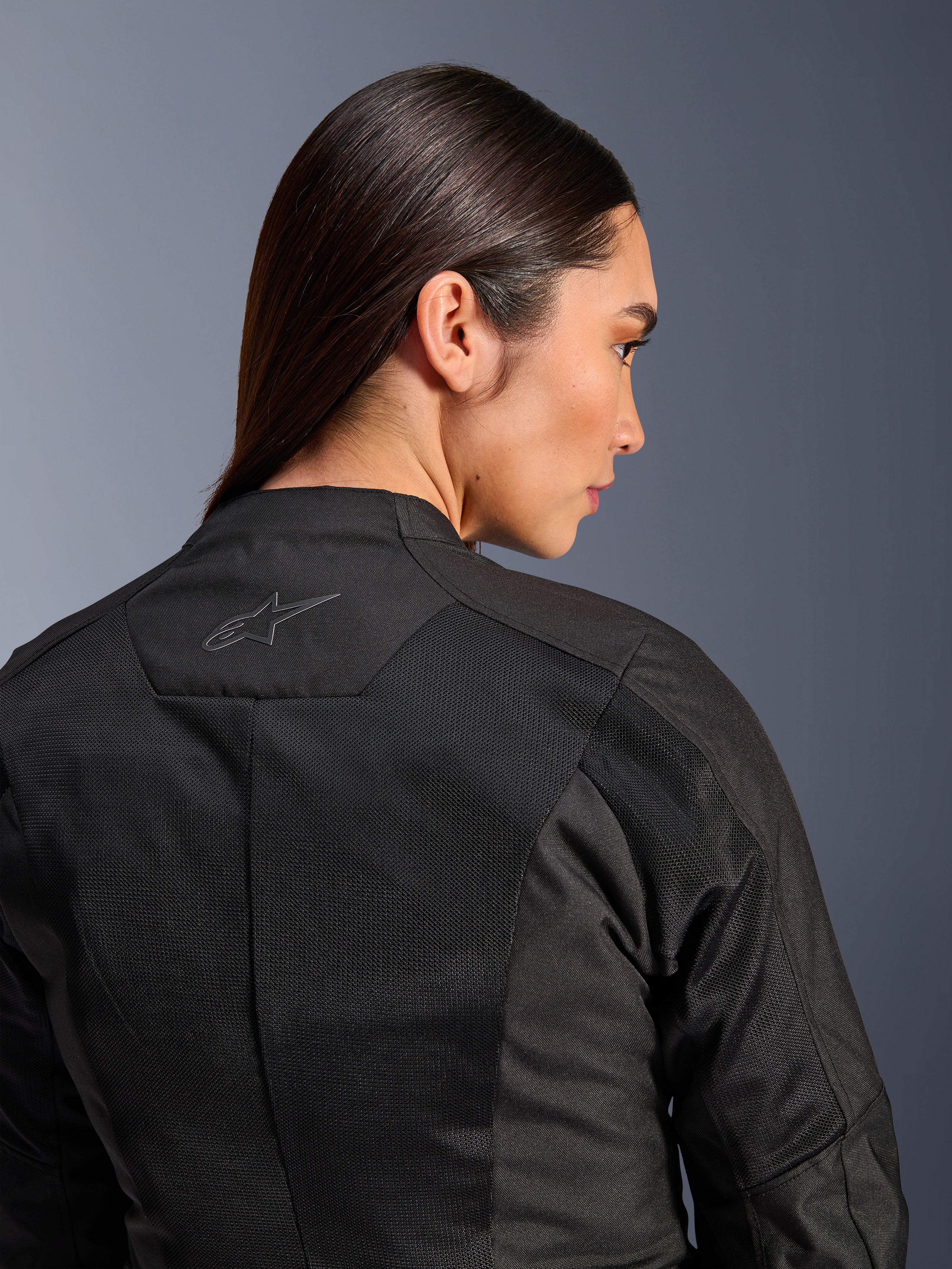 Giacca Alpinestars Stella C-1 Air da donna, giacca da moto in tessuto, nero, vista posteriore ravvicinata che mostra i pannelli di ventilazione in mesh tecnico e un logo a stella riflettente sulla parte superiore della schiena, abbigliamento moderno per la guida urbana