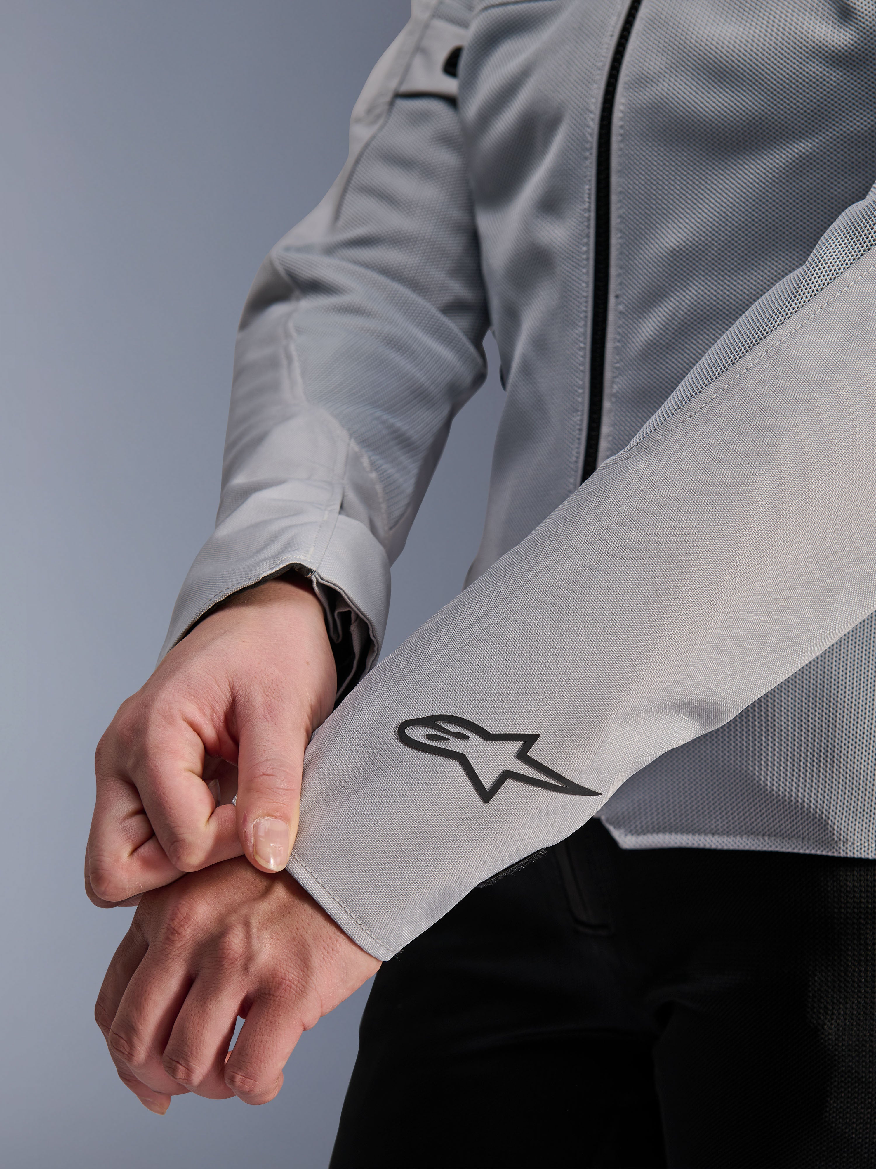 Primo piano della giacca Alpinestars Stella C-1 Air in Silver, con costruzione in rete tecnica e logo Alpinestars nero sulla manica sinistra, giacca da moto urbana da donna con branding riflettente.