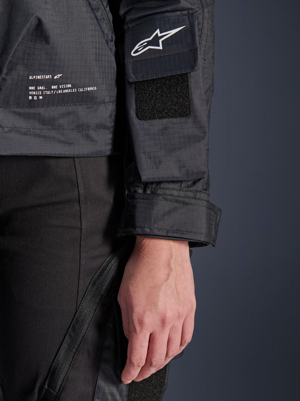 Alpinestars Molly Air Jacket, dettaglio ravvicinato del tessuto ripstop nero, logo Astar bianco sulla tasca della manica con toppa in velcro, polsino regolabile e testo del marchio stampato sul lato, abbigliamento moto urban da donna