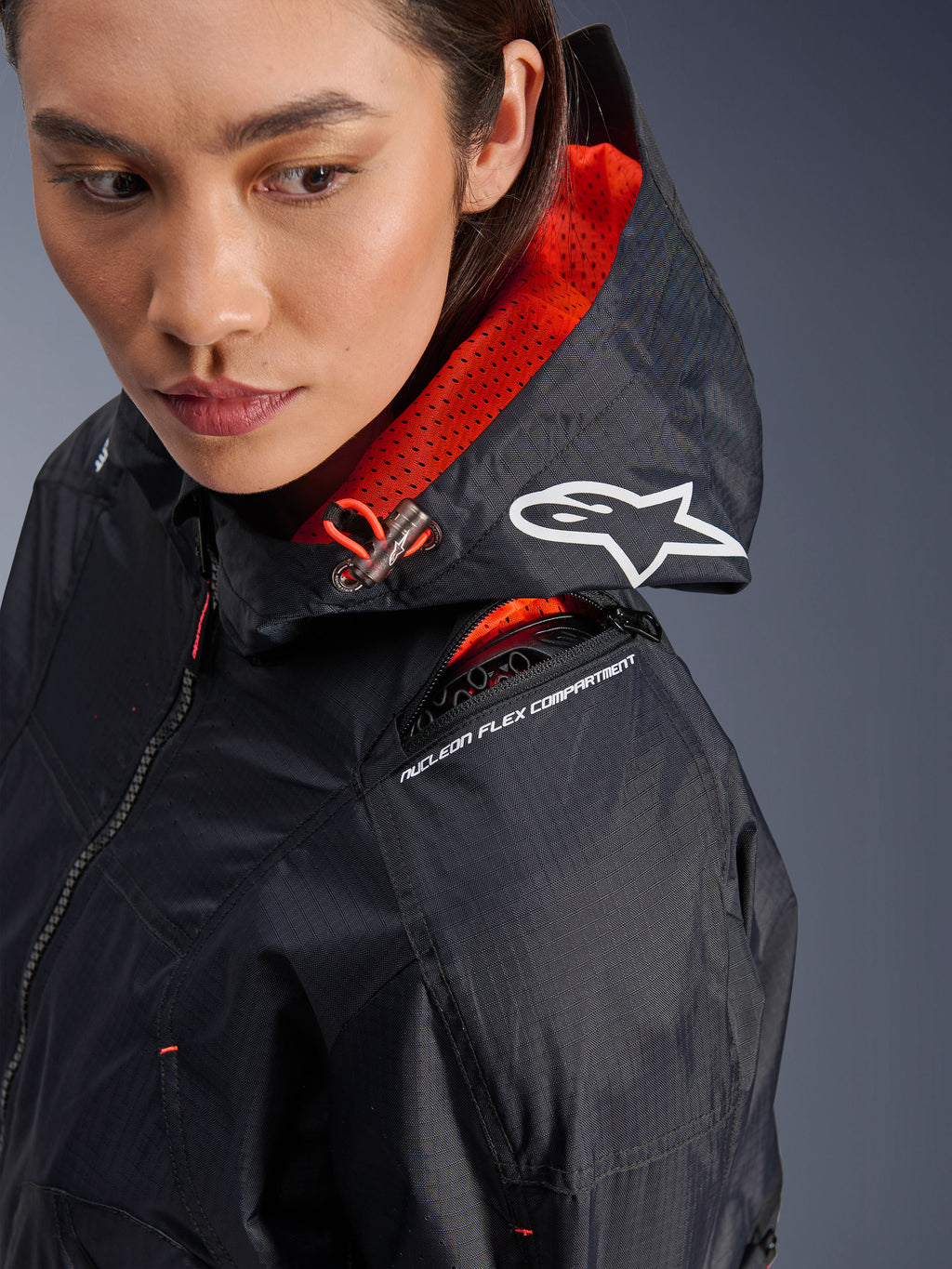 Alpinestars Molly Air Jacket, giacca da moto da donna, nero e corallo fluo, primo piano della spalla che evidenzia lo scomparto della protezione Nucleon Flex e logo Astars bianco sul cappuccio, abbigliamento urban riding in tessuto ripstop