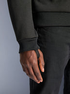 Alpinestars Chrome V2 Sport Hoodie, pile tecnico nero, primo piano del polsino a coste con passante per il pollice integrato per la stabilità alla guida, dettaglio abbigliamento moto urbano