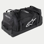 Alpinestars Komodo Travel Bag, grande borsa per attrezzatura da motocross in nero e antracite con loghi bianchi, dotata di ruote e maniglia telescopica, costruzione resistente per il trasporto di equipaggiamento da gara