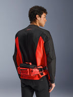 Alpinestars MM93 Waist Bag, borsa a vita da moto, rosso brillante e nero, indossata sopra una giacca da moto coordinata nera e rossa, con scomparti con cerniera e logo Marc Marquez MM93, struttura in tessuto resistente per il motociclismo