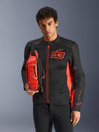 Uomo con borsa a vita Alpinestars MM93, rosso fluo e nero, indossata a tracolla sopra una giacca da moto coordinata nera e rossa, con logo Marc Marquez 93, design sportivo racing