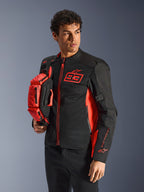 Alpinestars MM93 Waist Bag, borsa a vita in rosso fluo e nero, tenuta da un modello con giacca da moto coordinata nera e rossa, dotata di più scomparti con zip e logo Marc Marquez, accessorio pratico per la guida sportiva