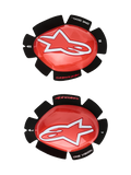 Alpinestars GP Tech Knee Sliders, rosso e bianco, protezioni ginocchio da moto racing, grande logo a stella bianco su plastica rossa lucida, scritta 'ONE GOAL. ONE VISION.' su supporto in velcro nero a forma di petalo, coppia destra e sinistra per uso in pista