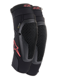 Ginocchiere Alpinestars Bionic Flex, nero e rosso, paio di ginocchiere da motocross con protezioni in tecnologia Nucleon Flex traforata, loghi Astars rossi e cinghie elasticizzate su una guaina in rete nera traspirante.
