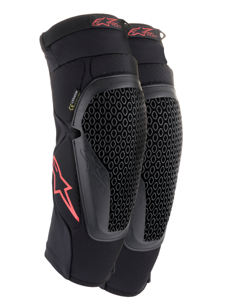 Ginocchiere Alpinestars Bionic Flex, nero e rosso, paio di ginocchiere da motocross con protezioni in tecnologia Nucleon Flex traforata, loghi Astars rossi e cinghie elasticizzate su una guaina in rete nera traspirante.