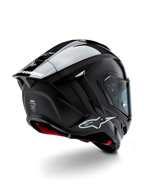 Casco Alpinestars Supertech R10 Solid, casco da racing per moto, finitura in carbonio nero opaco e lucido, vista posteriore a tre quarti che mostra la calotta in fibra di carbonio, lo spoiler aerodinamico e il marchio Alpinestars.