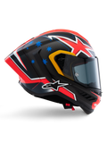 Casco Alpinestars Supertech R10 Miller Limited Edition, casco integrale racing, carbonio opaco con grafica rossa, bianca e blu, dettagli con stelle blu e rifiniture gialle della visiera, profilo aerodinamico con visiera scura fumé, equipaggiamento di sicurezza per moto ad alte prestazioni