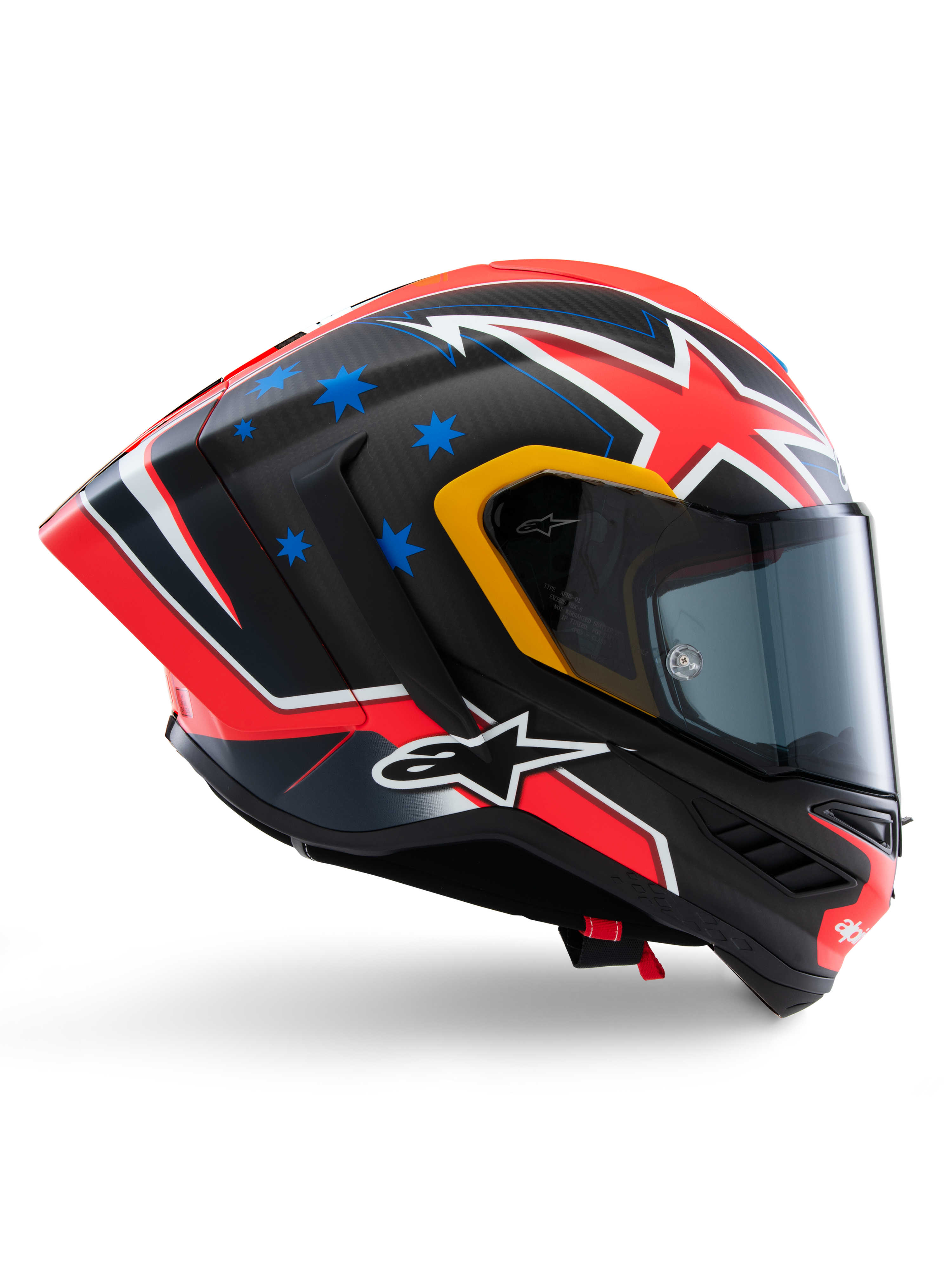 Casco Alpinestars Supertech R10 Miller Limited Edition, casco integrale racing, carbonio opaco con grafica rossa, bianca e blu, dettagli con stelle blu e rifiniture gialle della visiera, profilo aerodinamico con visiera scura fumé, equipaggiamento di sicurezza per moto ad alte prestazioni