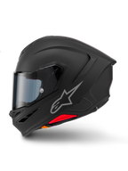 Casco Alpinestars S-R7 Solid, casco integrale da moto, nero opaco, vista laterale, con logo Astars argentato sul lato, design aerodinamico con spoiler integrato e prese d'aria sulla mentoniera, e accenti rossi e arancioni alla base.