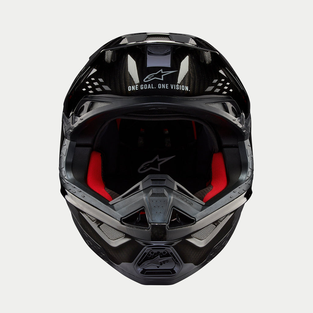 Casco Alpinestars Supertech M10 Solid, casco da motocross, carbonio nero lucido, vista frontale con imbottitura interna rossa, calotta in fibra di carbonio e slogan "ONE GOAL. ONE VISION." sulla zona della visiera