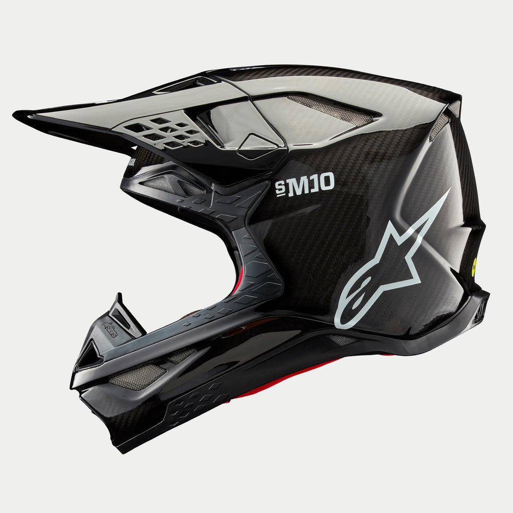 Casco Alpinestars Supertech M10 Solid, casco da motocross, carbonio nero lucido, profilo laterale con trama in fibra di carbonio a vista, marchio SM10 e logo Alpinestars bianchi, design aerodinamico con prese d'aria coperte da rete