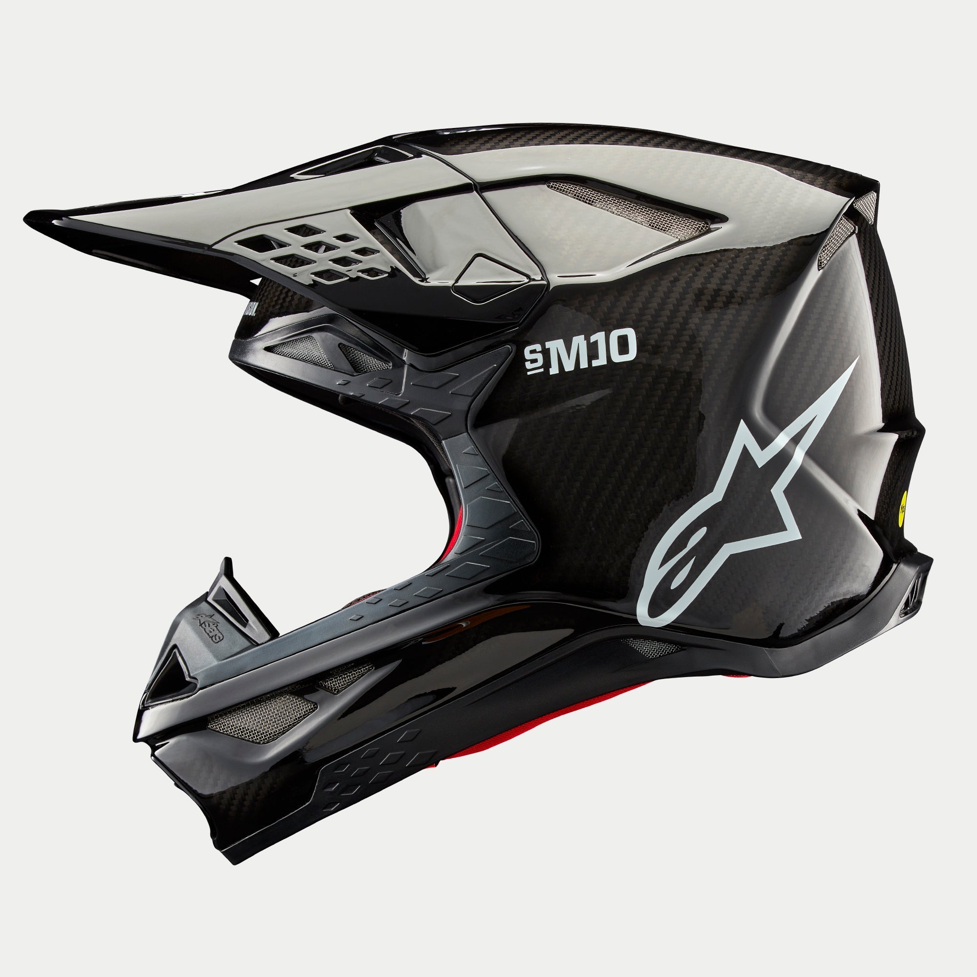 Casco Alpinestars Supertech M10 Solid, casco da motocross, carbonio nero lucido, profilo laterale con trama in fibra di carbonio a vista, marchio SM10 e logo Alpinestars bianchi, design aerodinamico con prese d'aria coperte da rete
