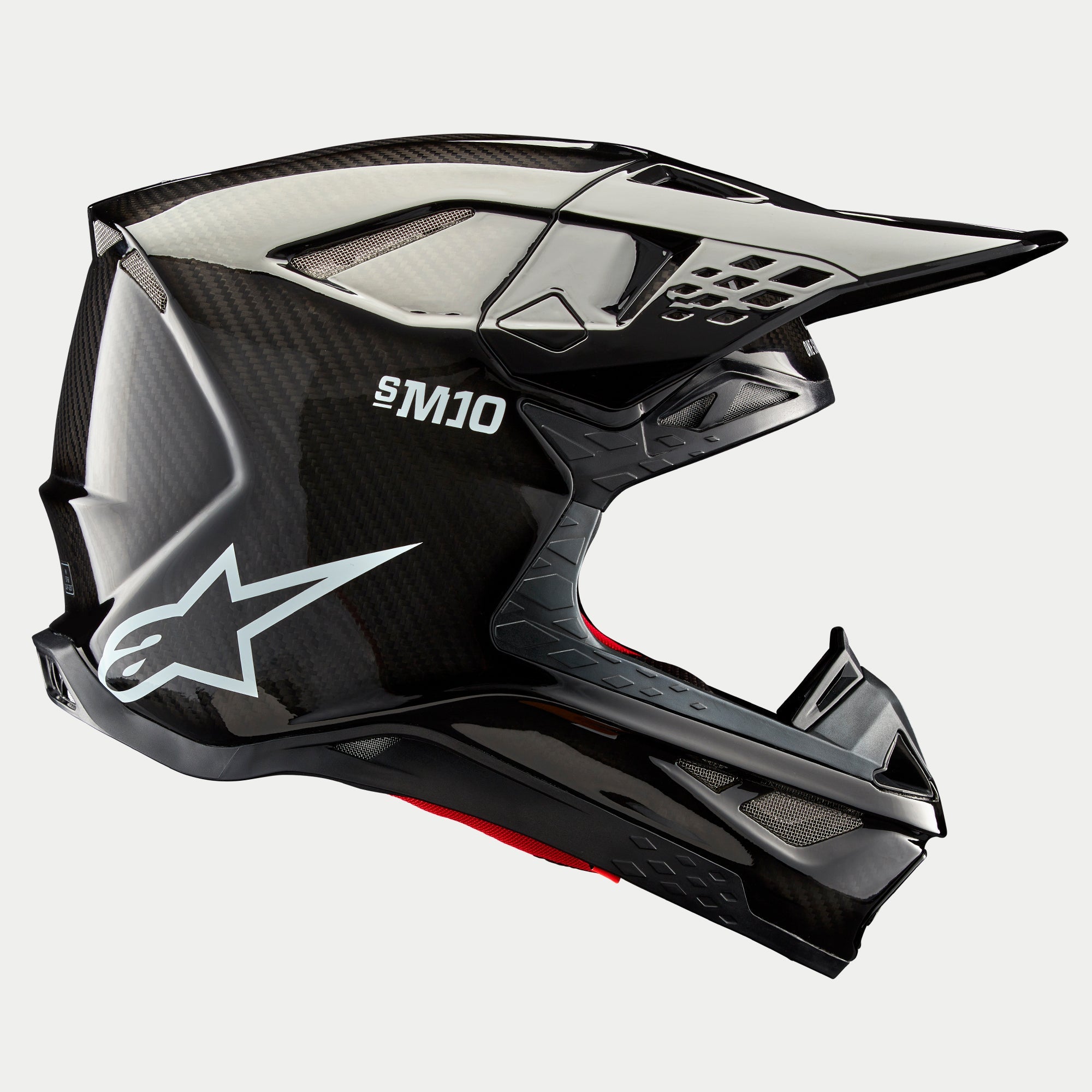 Casco Alpinestars Supertech M10 Solid, Carbonio Nero Lucido, casco da motocross, vista laterale del profilo che mostra la trama della fibra di carbonio lucida, marchio S-M10, logo Alpinestars a stella bianco, design aerodinamico con frontino e prese d'aria