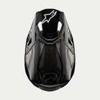 Casco Alpinestars Supertech M10 Solid, casco da motocross, carbonio nero lucido, vista dall'alto con trama in fibra di carbonio a vista, logo Astars bianco sulla visiera, profilo aerodinamico con porte di ventilazione integrate