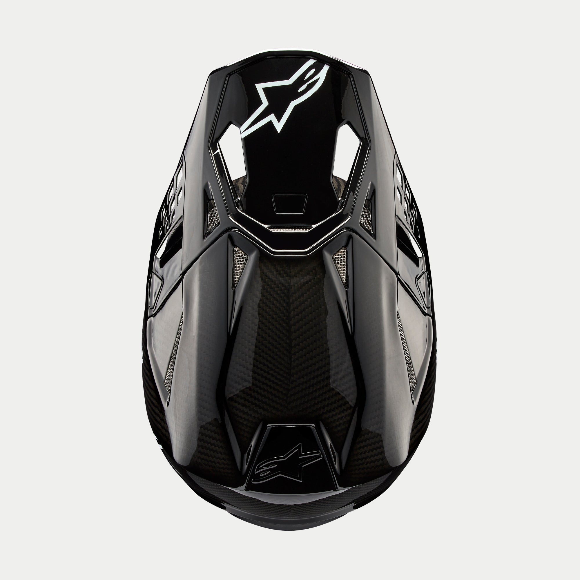 Casco Alpinestars Supertech M10 Solid, casco da motocross, carbonio nero lucido, vista dall'alto con trama in fibra di carbonio a vista, logo Astars bianco sulla visiera, profilo aerodinamico con porte di ventilazione integrate