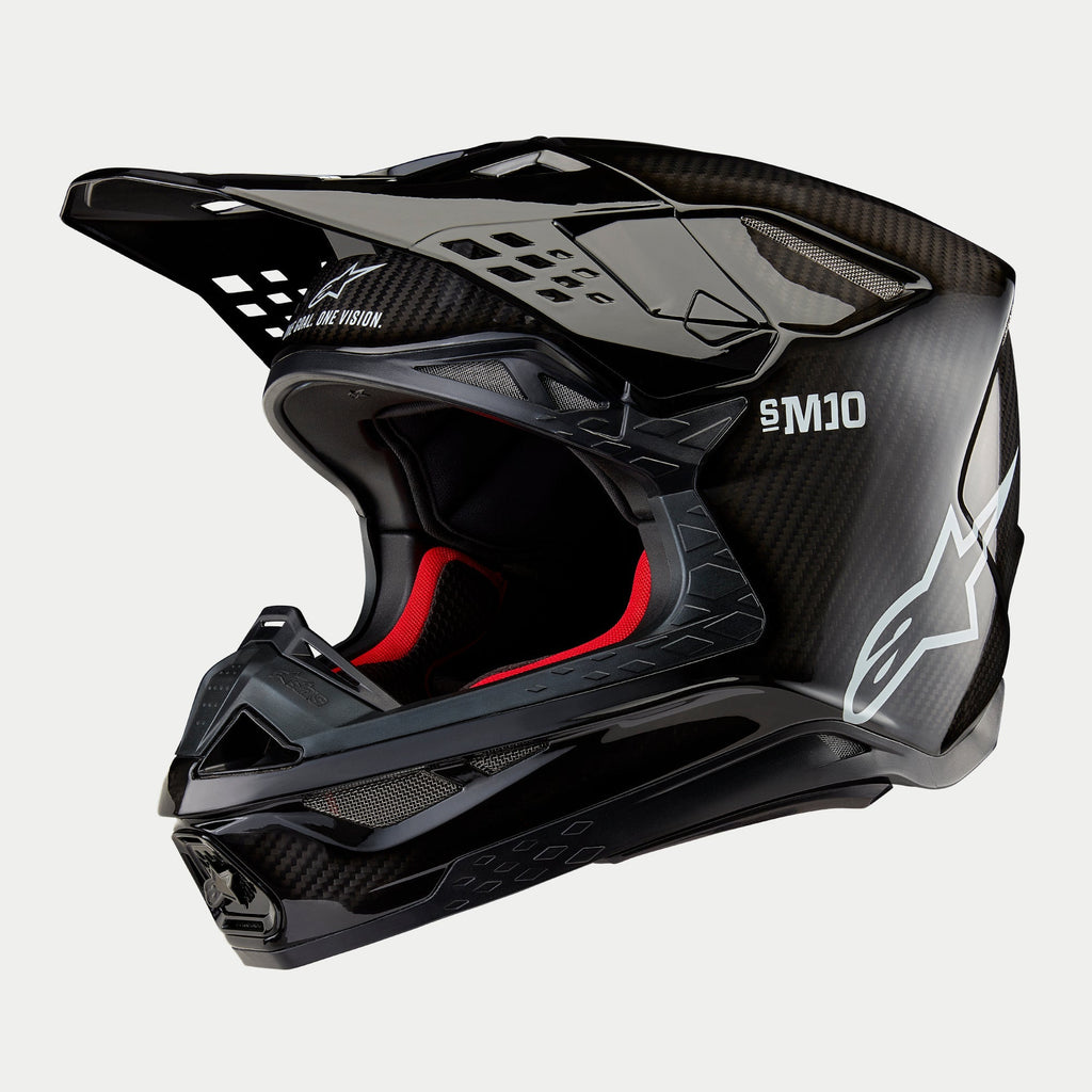 Casco Alpinestars Supertech M10 Solid, casco da motocross, carbonio nero lucido con trama in fibra a vista, logo Alpinestars bianco e marchio SM10, fodera interna rossa, design aerodinamico con molteplici prese d'aria
