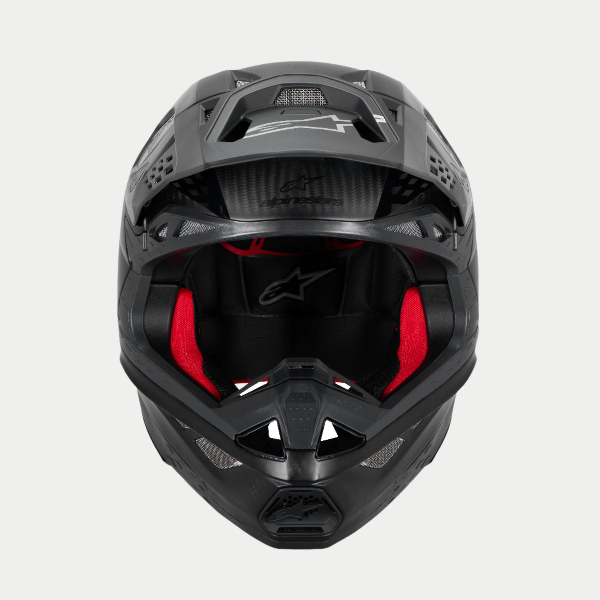 Casco Alpinestars Supertech M10 Fame ECE 22.06, casco da motocross, carbonio nero opaco e lucido, vista frontale con imbottitura interna rossa visibile, calotta aerodinamica in fibra di carbonio, design ventilato per gare fuoristrada