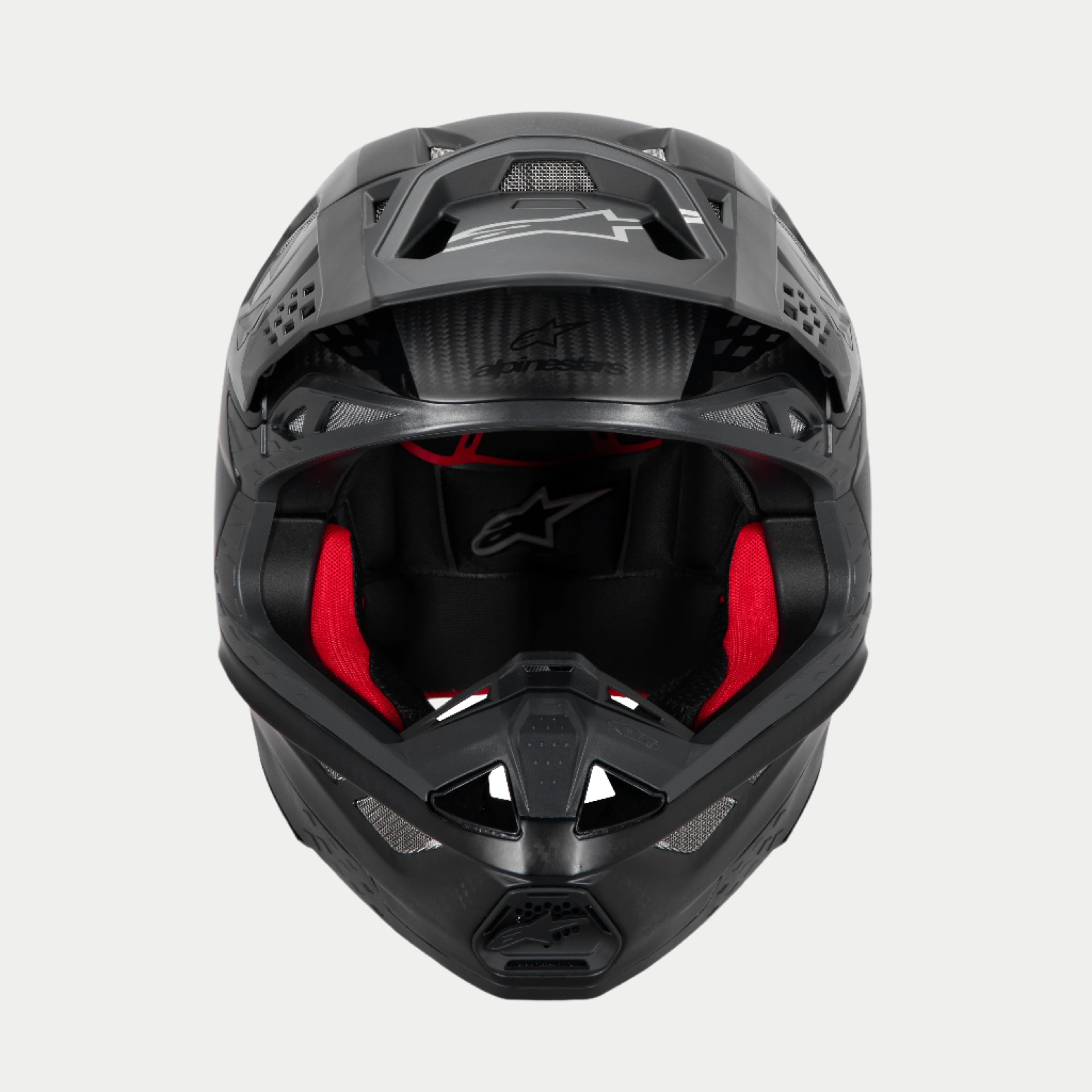 Casco Alpinestars Supertech M10 Fame ECE 22.06, casco da motocross, carbonio nero opaco e lucido, vista frontale con imbottitura interna rossa visibile, calotta aerodinamica in fibra di carbonio, design ventilato per gare fuoristrada