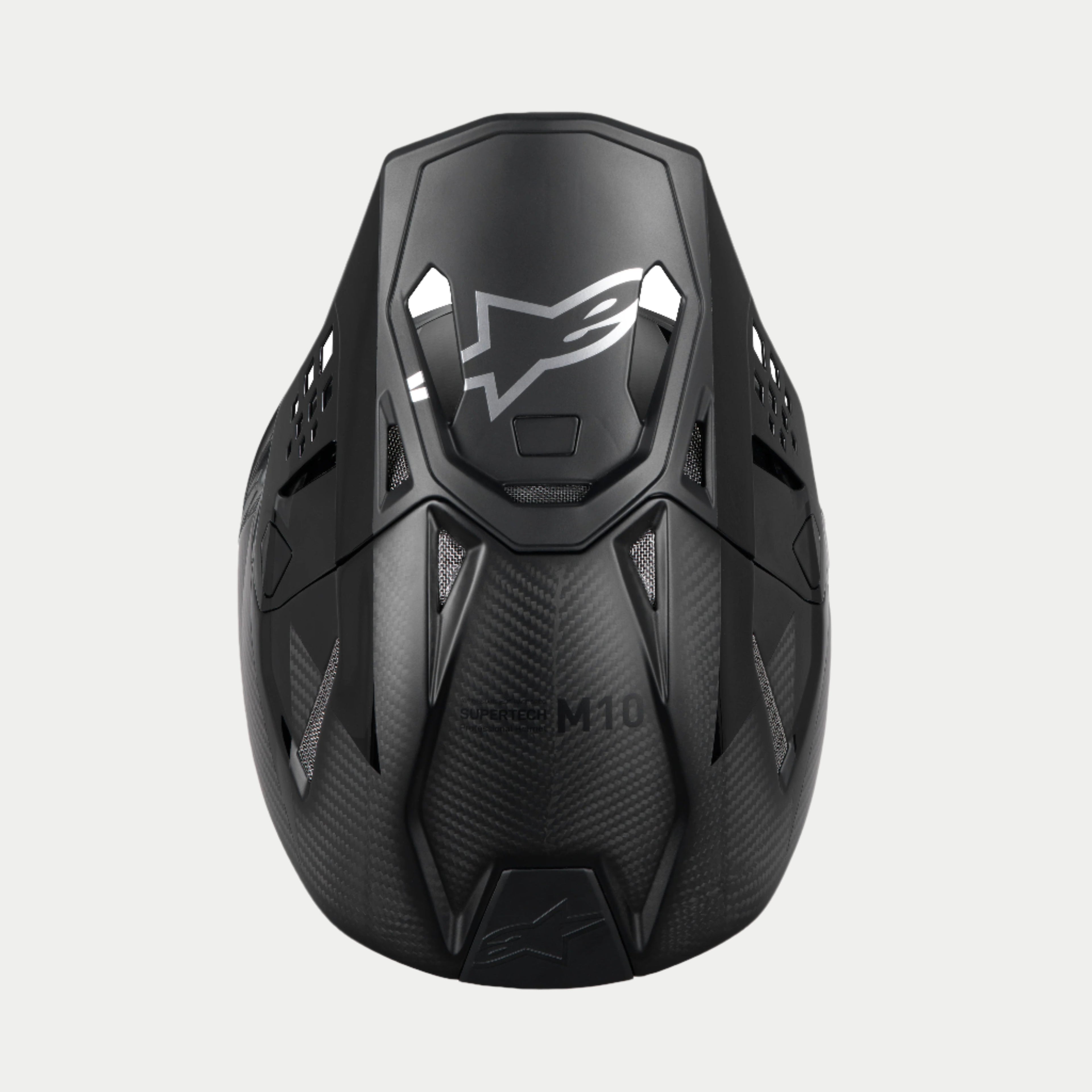 Casco Alpinestars Supertech M10 Fame ECE 22.06, casco da motocross, nero carbonio opaco e lucido, vista dall'alto che mette in risalto la trama in fibra di carbonio, visiera aerodinamica con logo Alpinestars argento e numerose porte di ventilazione per corse off-road.