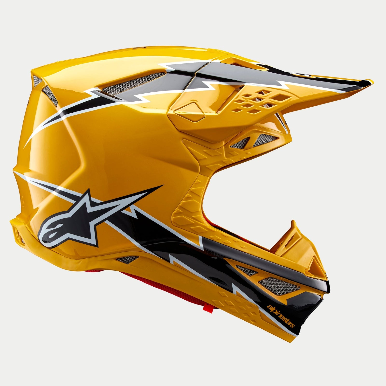 Casco Alpinestars Supertech M10 Ampress, casco da motocross, nero e giallo lucido, profilo laterale con calotta aerodinamica in carbonio e grafiche audaci e frastagliate, molteplici prese d'aria e design racing elegante