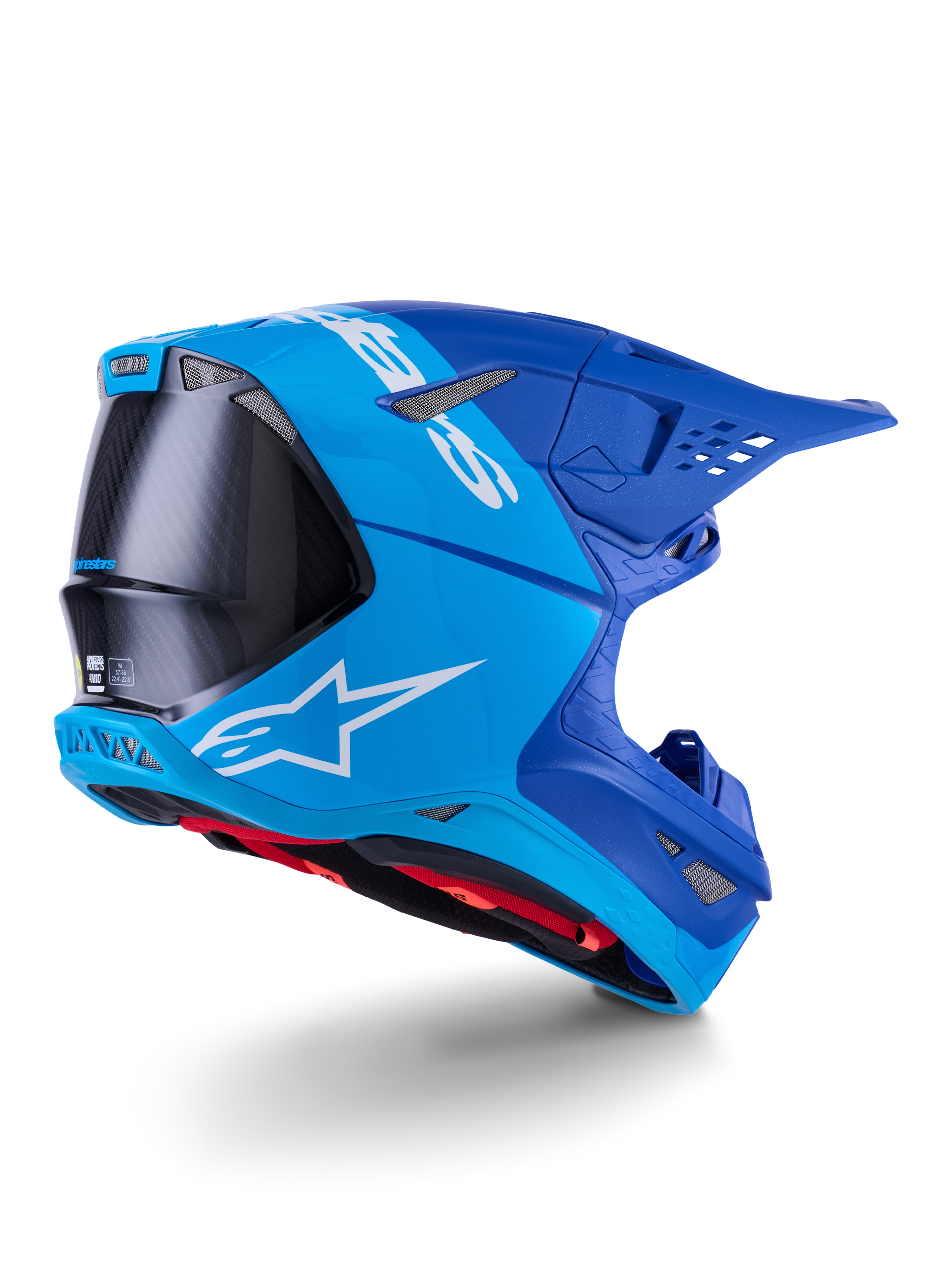 Casco Alpinestars Supertech M10 Flood, casco da motocross, azzurro e blu navy con fibra di carbonio nera a vista, profilo posteriore-laterale che mostra le porte di ventilazione e il logo bianco, interno rosso, design aerodinamico avanzato per prestazioni off-road