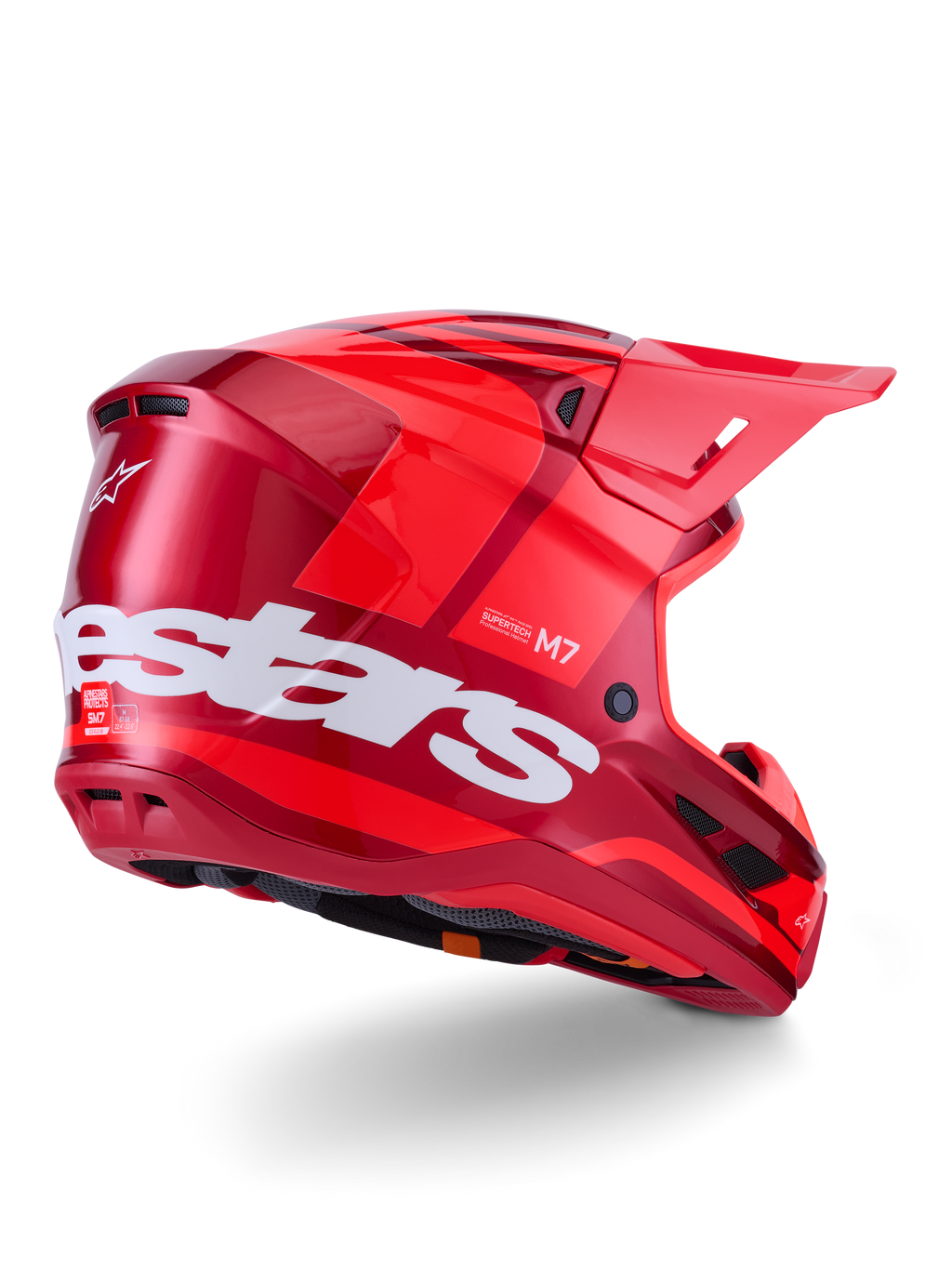 Casco Alpinestars S-M7 Core, casco da motocross, rosso lucido con grande logo Alpinestars bianco sul lato, dotato di calotta aerodinamica, prese d'aria integrate e visiera protettiva, vista posteriore a 3/4