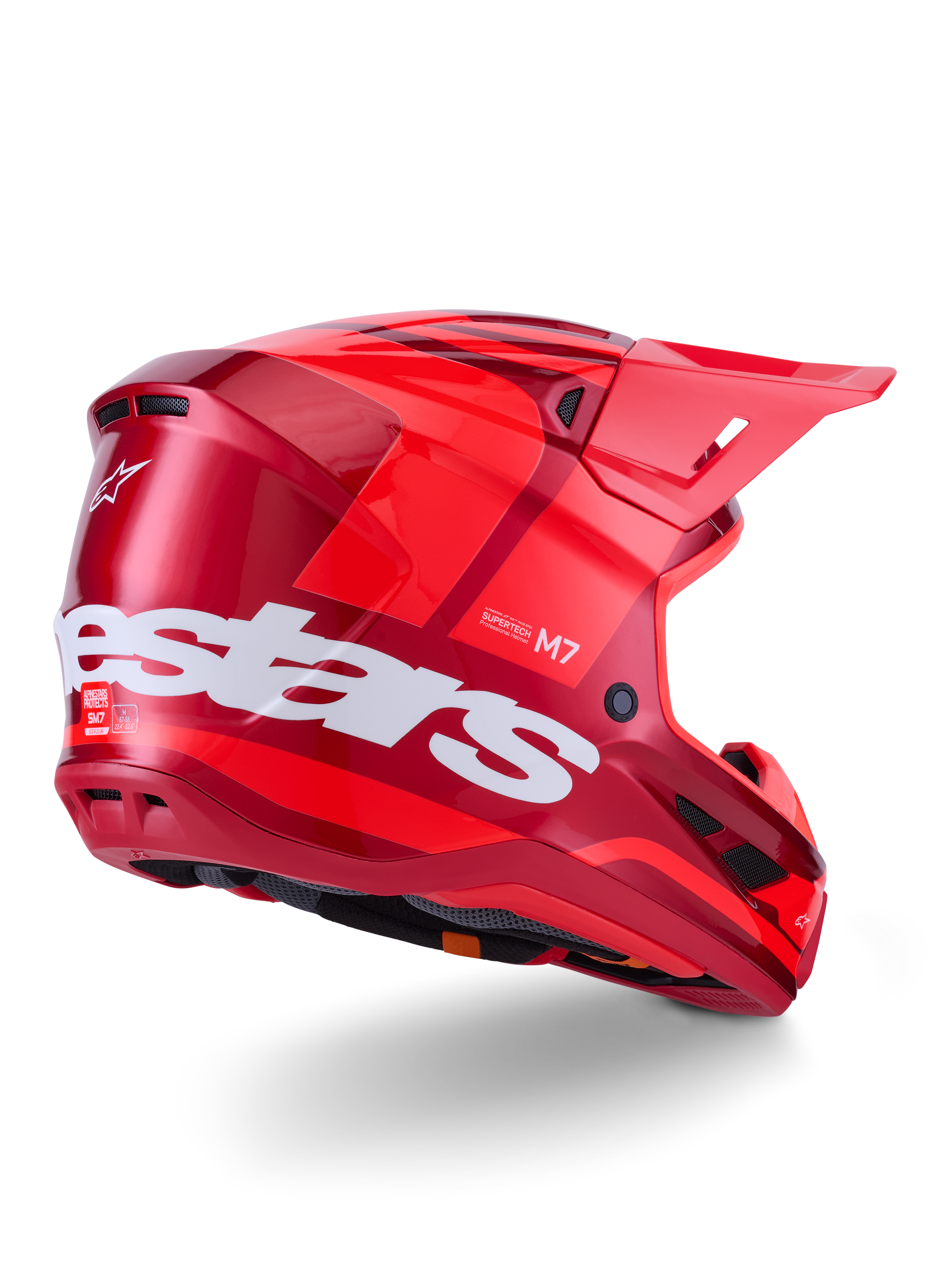 Casco Alpinestars S-M7 Core, casco da motocross, rosso lucido con grande logo Alpinestars bianco sul lato, dotato di calotta aerodinamica, prese d'aria integrate e visiera protettiva, vista posteriore a 3/4