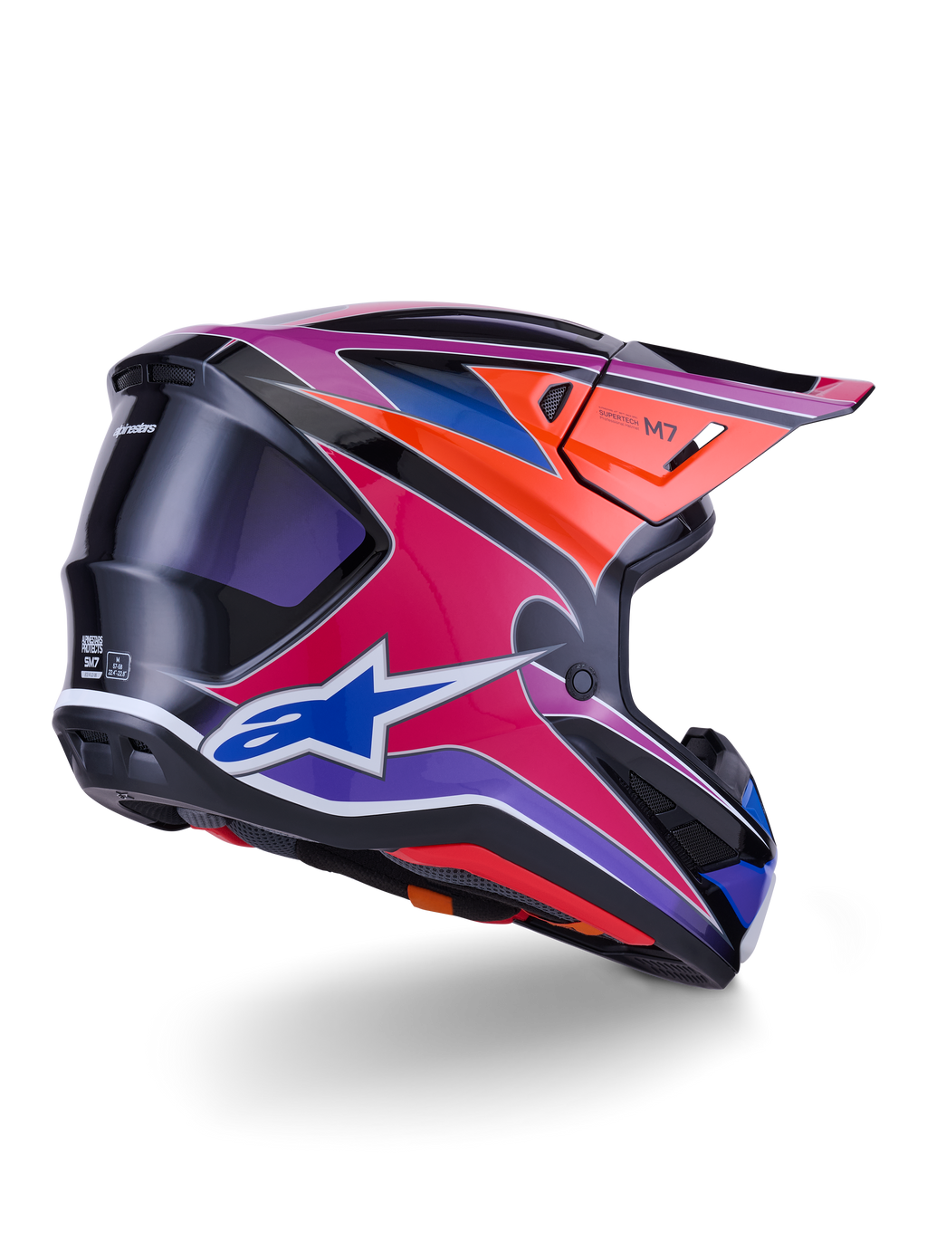 Casco Alpinestars S-M7 Fuse, casco da motocross, finitura lucida blu, viola e rosa con accenti arancioni e neri, vista posteriore a tre quarti che mostra la calotta aerodinamica, la visiera e le prese di ventilazione, protezione professionale per gare fuoristrada