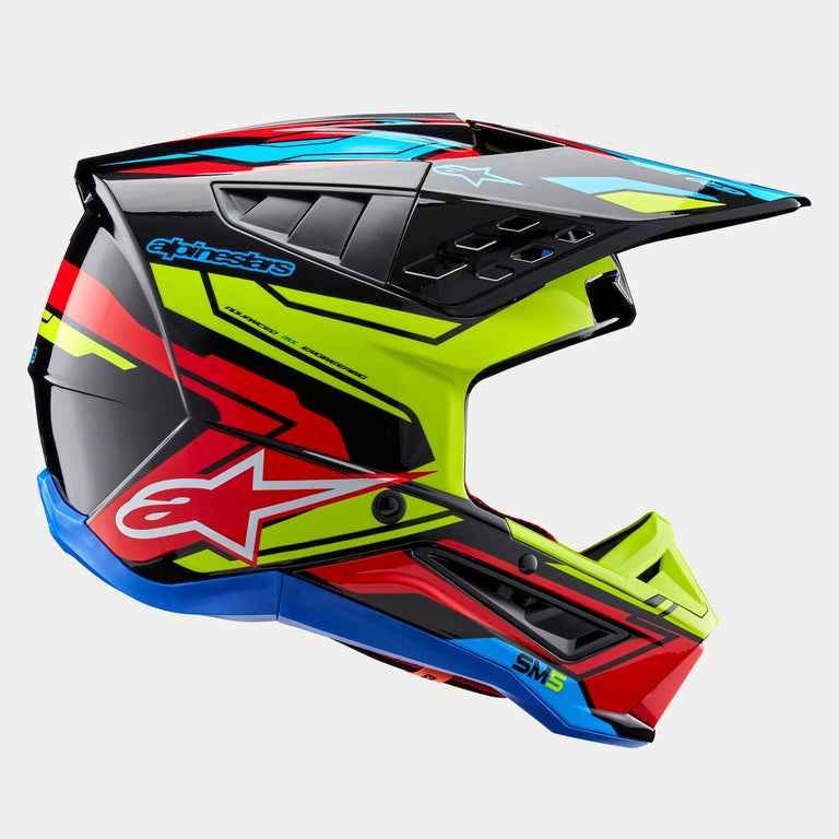 Casco Alpinestars S-M5 Action 2 ECE, casco da motocross, grafica nero lucido con giallo fluo, rosso brillante e blu ciano, vista laterale con calotta aerodinamica, frontino ventilato e logo Alpinestars sul lato, protezione professionale per corse fuoristrada