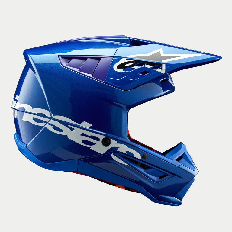 Alpinestars S-M5 Corp Helmet ECE, casco da motocross blu lucido, vista di profilo laterale, logo Alpinestars bianco sul lato, accenti viola nelle porte di ventilazione, calotta aerodinamica leggera per prestazioni off-road