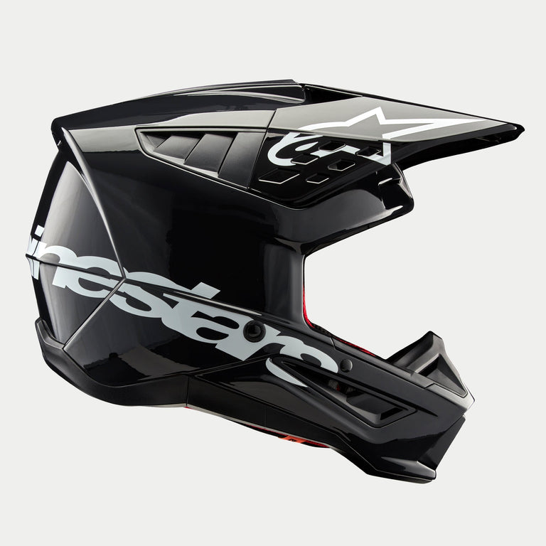 Casco Alpinestars S-M5 Corp, casco da motocross, grigio scuro lucido, vista laterale di profilo con grande logo Alpinestars bianco, logo a stella bianco sulla visiera, eleganti prese d'aria aerodinamiche, finitura lucida, protezione per corse fuoristrada