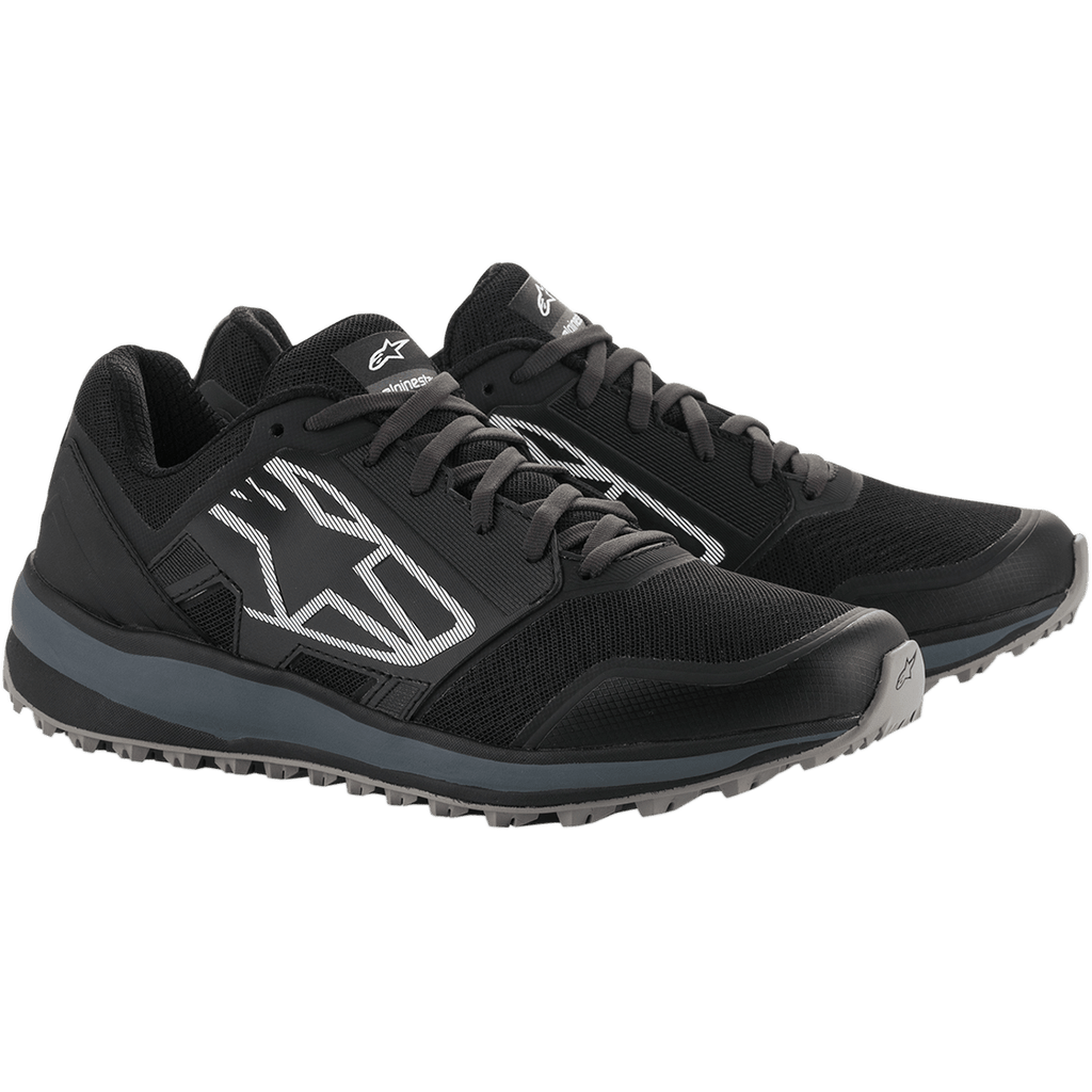 Scarpe Alpinestars Meta Trail, scarpe da running ad alte prestazioni, nero e grigio scuro, grande logo Astars a strisce bianche sul lato, design stringato con suola grigia robusta, progettate per il comfort tutto il giorno nel paddock