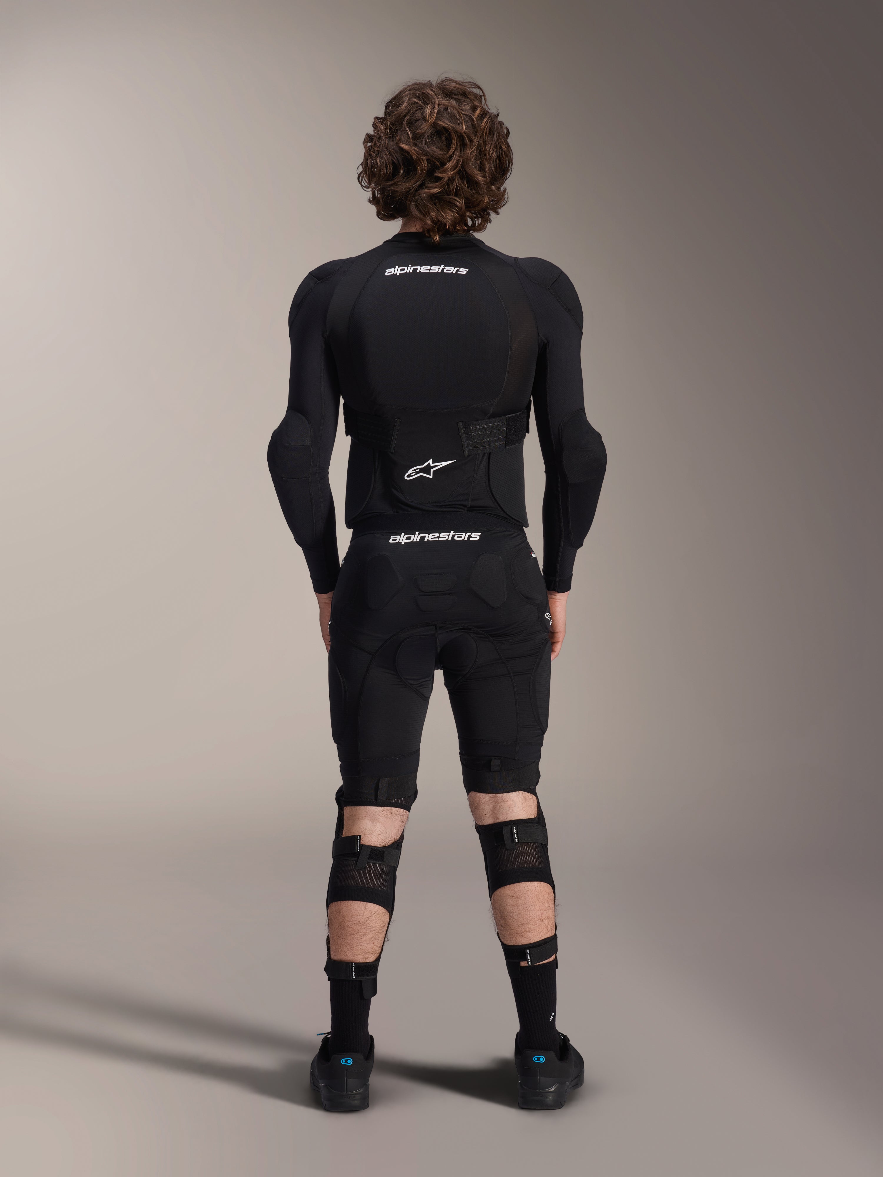 Alpinestars A-Impact Plasma Protection Jacket - Maniche Lunghe, vista posteriore, nera con loghi Alpinestars bianchi, indossata con pantaloncini protettivi e ginocchiere per una protezione completa da mountain bike