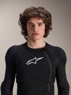 Modello uomo che indossa la Giacca protettiva Alpinestars A-Impact Plasma a maniche lunghe, nera con logo Astars bianco, dotata di cerniera frontale asimmetrica e imbottiture integrate, protezione professionale per MTB