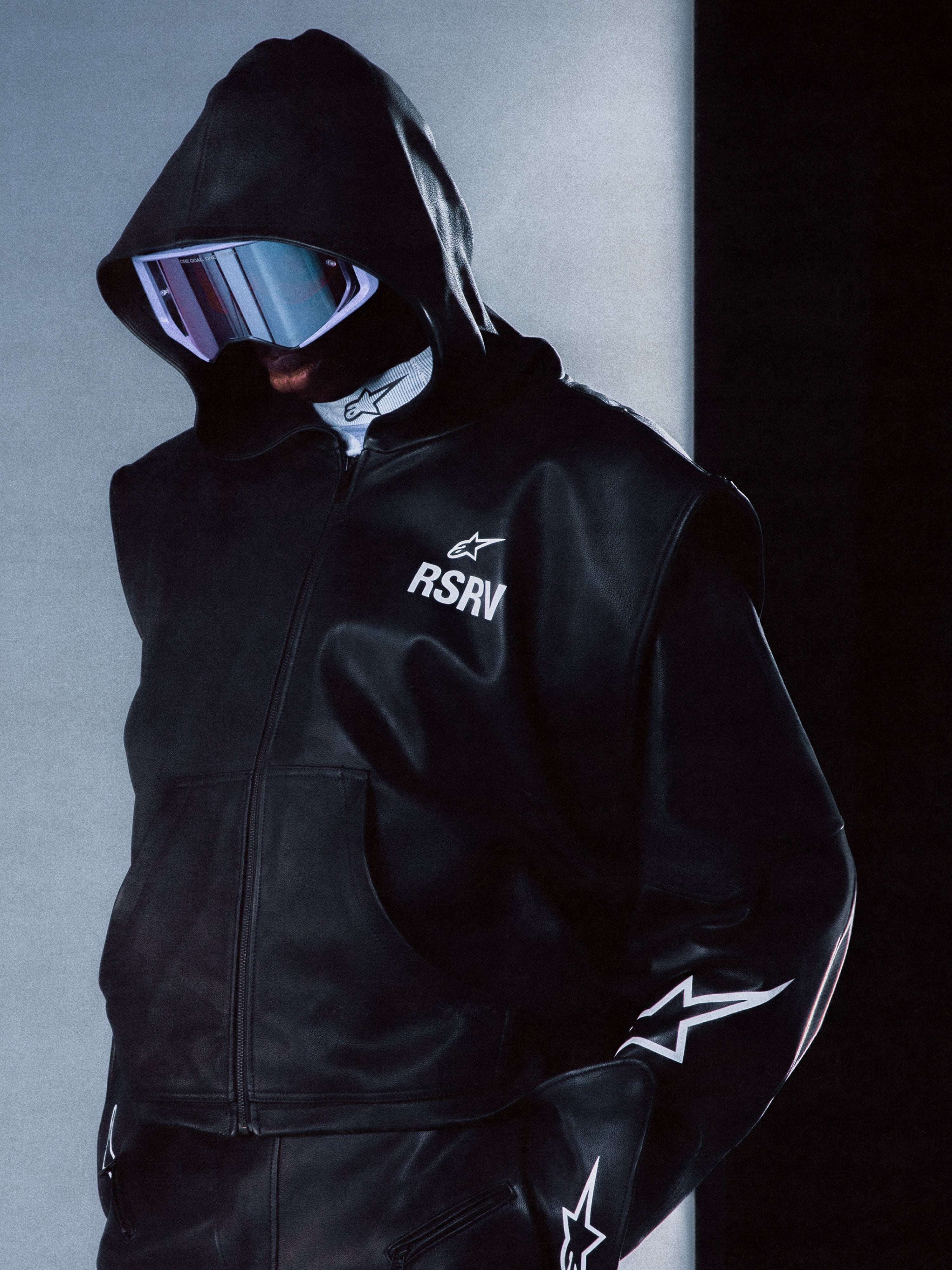 Alpinestars RSRV Axis Leather Hoodie, giacca con cappuccio in pelle nera, logo RSRV e stella, design stelle bianche sulle maniche, stile urbano premium, texture lucida